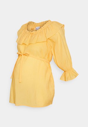 Vestido amarelo com decote franzido, mangas bufantes longas e cintura atada. Feito de um tecido texturizado com riscas verticais.