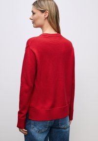 Maglione rosso a maglia con orlo e polsini a costine, caratterizzato da una vestibilità comoda e un classico collo a giro, realizzato in materiale morbido.