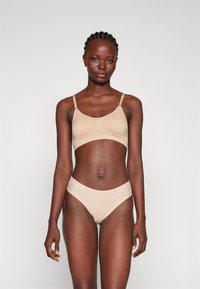 Naha bezešvá braletka a bikinová souprava. Měkká tkanina, minimalistický design, nastavitelné ramínka a vysoký střih pro pohodlí a padnutí.