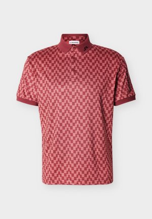 Polo rouge à motif géométrique en damier, col boutonné, avec logo sur le col gauche et la manche droite.