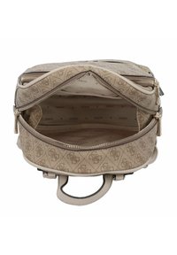 Mochila beige con un patrón y múltiples compartimentos con cierre, que presenta una textura suave y un interior marcado con el nombre de la marca "GUESS".