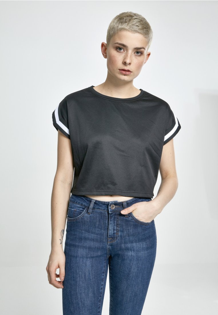 Kraftig sort t-shirt med korte ærmer, med hvide detaljer på manchetten. Parret med mørkeblå denim jeans, minimalistisk design.