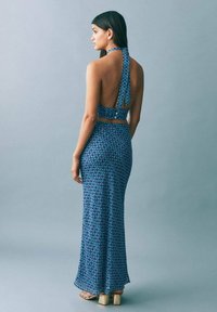 Modrý kvetinový dvojdielny outfit s halter topom so šnúrkou na chrbte a rybičkovou sukňou s priliehavým strihom a jemným leskom.