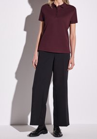 Bordeauxfärgad polotröja med treknappslå, i kombination med svarta vida byxor och svarta läderskor. Texturerad tyg, ren design.