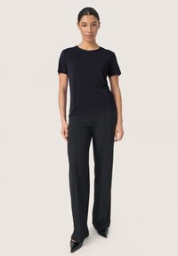 T-shirt navy a maniche corte con scollo rotondo abbinato a pantaloni neri su misura e décolleté neri con punta. Tessuto liscio e design aderente.
