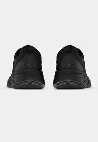 Μαύρα αθλητικά παπούτσια με υφασμένο καουτσούκ σόλα, πίσω λωρίδα για το τράβηγμα και διακριτική λεπτομέρεια λογότυπου στη φτέρνα. Κομψός, σύγχρονος σχεδιασμός.