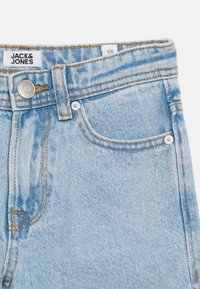 Φωτεινό μπλε τζιν παντελόνι με μπροστινή τσέπη, μεταλλικό κουμπί και ετικέτα της μάρκας Jack & Jones στη μέση, εμφανής ετικέτα μεγέθους 128.