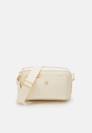 Beige rektangulær skuldertaske med justerbar rem, frontlomme, gyldent lynlås og gyldent mærkelogo på frontlommen.