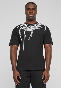 Sort bomulds T-shirt med et hvidt grafik af sammenfiltrede snørebånd over skuldrene. Kortærmet og en afslappet pasform.
