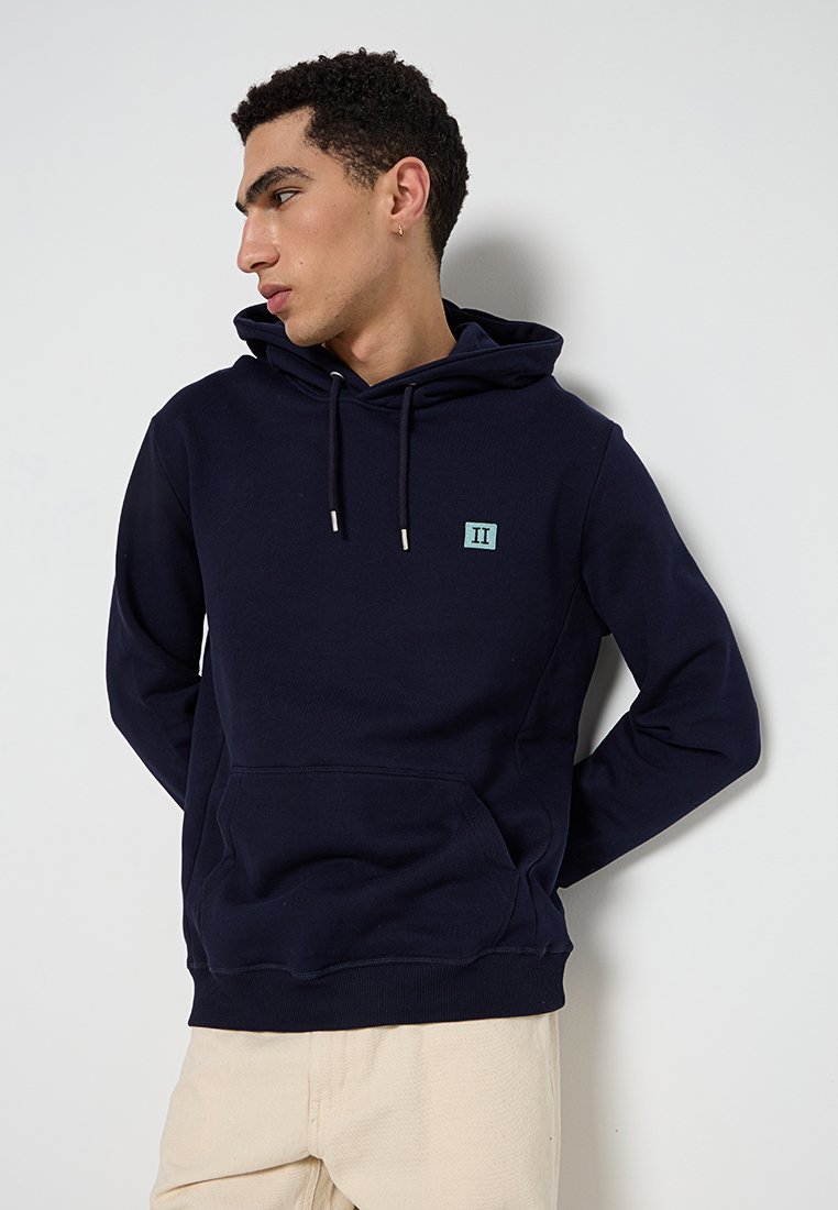 Felpa blu navy in morbido cotone, dotata di una tasca frontale, coulisse regolabile e un piccolo logo ricamato sul petto.