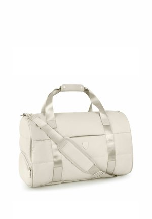 Bolsa de lona acolchada color beige claro con doble asa, correa de hombro ajustable, bolsillo lateral con cremallera y bolsillo delantero con solapa y logo sutil.