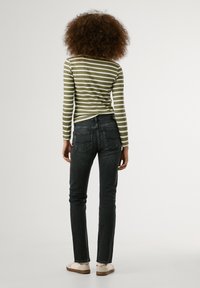 Zaļš un balts svītrots krekls ar garām piedurknēm, pieguļošs dizains. Tumši džinsi ar piecām kabatām un nelielu izbalējumu. Ikdienišķi apavi ar dekoratīviem akcentiem.