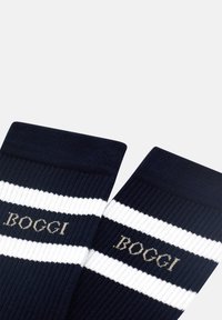 Marinblå ribbade strumpor med vita ränder och "BOGGI" logotyp i guld. Inkluderar ett tjockt avslut för komfort och en mjuk textur.