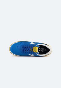 Zapatilla deportiva azul con diseño de estrella blanca, parte superior sintética texturizada, acentos amarillos, plantilla negra y cordones planos.