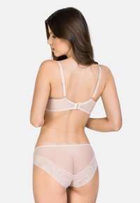 Set di lingerie beige con reggiseno trasparente a spalline regolabili e culotte trasparenti coordinate. Delicati bordi a scallop e texture morbida.