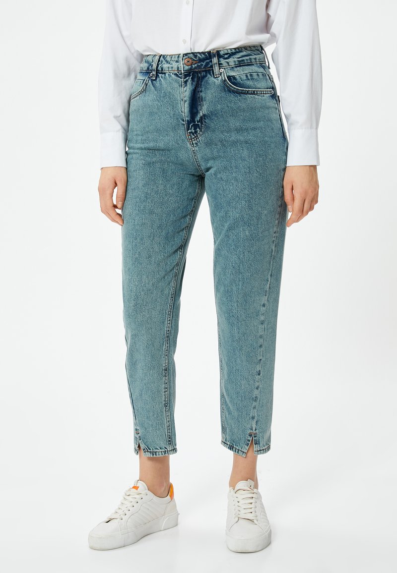 Ljust blå högmidjade jeans gjorda av denim. Funktioner inkluderar rak skärning med ankle slits, stickade detaljer och knappstängning.