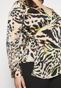 Leopardenmuster Wickelbluse in Beige, Schwarz und Grün. Lange Ärmel mit einem Bindeband in der Taille. Glatte, seidenähnliche Textur.