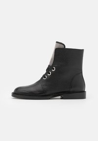 Czarne skórzane botki za kostkę o teksturowanej powierzchni, z dwoma otworami na sznurowadła, gładką podeszwą i kontrastowym szarym panelem elastycznym.
