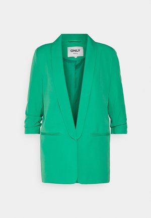 Blazer verde da donna con maniche arrotolate, rever a incavo e due tasche frontali a fessura. Etichetta "ONLY tailoring" all'interno del colletto.