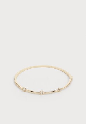 Gullfarget metallbanglearmbånd med tre små klare fasetterte steiner, rund form, glatt overflate og minimalistisk design.