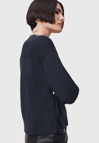 Maglione blu scuro con una vestibilità rilassata, maniche lunghe, orlo a coste e spacco laterale. Realizzato in un morbido tessuto a maglia con una superficie liscia.