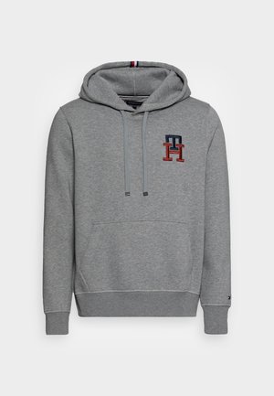 Harmaa huppari, joka on valmistettu pehmeästä kankaasta ja jossa on etupuolella kengurupussi sekä punaisella ja laivastonsinisenä brodeerattu logo.