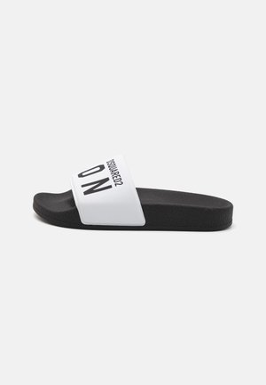 Sandale à semelle plate en noir et blanc, avec une épaisse sangle blanche imprimée avec "DSQUARED2" et "ICON" en lettres noires en gras.