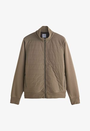 Barna cipzáros dzseki magas gallérral, steppelt elülső résszel és oldalsó zsebekkel. Simább, könnyű anyagból készült, bordás mandzsettákkal.