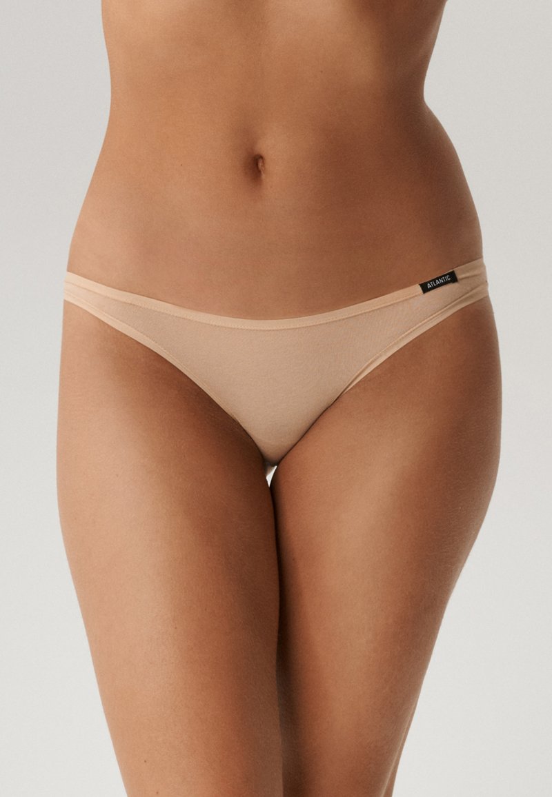 Beżowe stringi wykonane z miękkiej tkaniny, z cienkimi bokami i małą metką z logo. Posiadają gładki, minimalistyczny design.