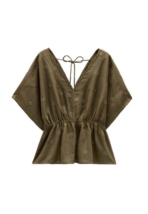 Oliwkowa bluzka z krótkim rękawem, dekoltem w kształcie litery V, marszczoną talią i haftem w kwiaty. Posiada detal w postaci wiązania z tyłu.