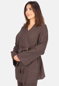 Brauner, strukturierter Kimono-Robenstil mit weiten Ärmeln und einem Taillengurt, aus weichem Stoff gefertigt. Verfügt über einen V-Ausschnitt und eine lockere Silhouette.