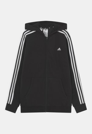Zwarte zip-up hoodie van zachte stof, met een capuchon, twee voorzakken en drie witte strepen langs de mouwen. Adidas-logo op de borst.