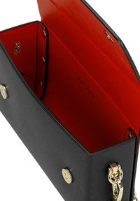 Borsa a mano rettangolare nera con fodera interna rossa, chiusure a scatto magnetico dorate e una tracolla dorata attaccata di lato.