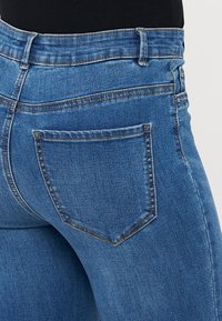 Hubené modré džíny z denimu s středně vysokým pasem a zadní kapsou s jemným diagonálním švem.