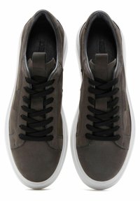 Sneakers in pelle grigia con lacci neri, punta rotonda e suola in gomma bianca. Presentano dettagli di cucitura lungo i lati.