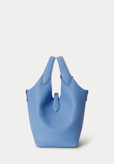 Τσάντα από μπλε δερμάτινο ύφασμα με υφή βότσαλου, με δύο χερούλια και μια μικρή λουρίδα λεπτομέρεια στο μπροστινό μέρος, στέκεται όρθια σε απλό φόντο.