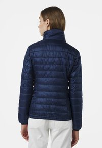 Marinblå puffjacka med hög krage, med quiltad design och förlängda ärmar, tillverkad av glänsande, slätt material.