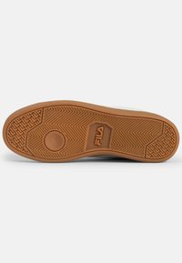 Gumitalpú sneaker, texturált felülettel, kör alakú logóval és mintás talpakkal, krémszínben. Klasszikus sportcipő sziluett.
