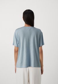 T-shirt azzurro chiaro a maniche corte realizzato in tessuto morbido e liscio. Presenta un colletto tondo e una vestibilità rilassata con una leggera lucentezza.