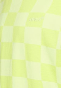 Světlá žlutá kockovaná košile od Levi's, vyrobená z jemného materiálu s jemně reliéfním logem ve sladěné barvě, které zdůrazňuje rastr.