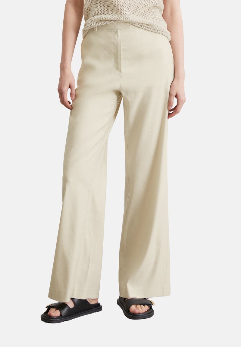 Lichtbeige wijde broek van zachte stof met een gladde textuur, voorzien van een hoge taille en zijnaadzakken.