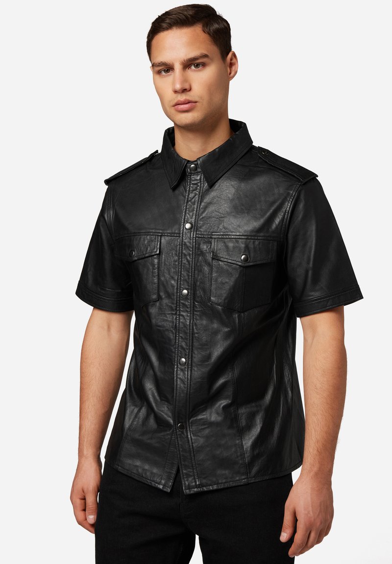 Zwart leren kortemouwen shirt met een knoopsluiting aan de voorkant, twee borstzakken, schouderepauletten en een gladde, gestructureerde afwerking.