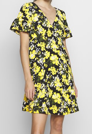 Robe fleurie sur fond noir, ornée de fleurs jaunes et blanches. Encolure en V, manches courtes flottantes et coupe décontractée.