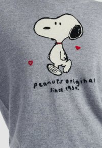 Grijze sweatshirt met een geborduurd Snoopy-ontwerp met rode accenten en de tekst "peanuts original since 1950." Zachte textuur.
