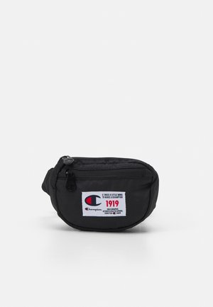 Schwarze Champion Gürteltasche mit vorderer Reißverschlusstasche und weißem rechteckigem Markenetikett mit Logo und rotem Text "1919".