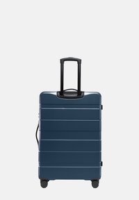 Tvrdý kufr tmavě modré barvy s vodorovnými drážkami, teleskopickou černou rukojetí a čtyřmi černými kolečky pro snadnou manipulaci.