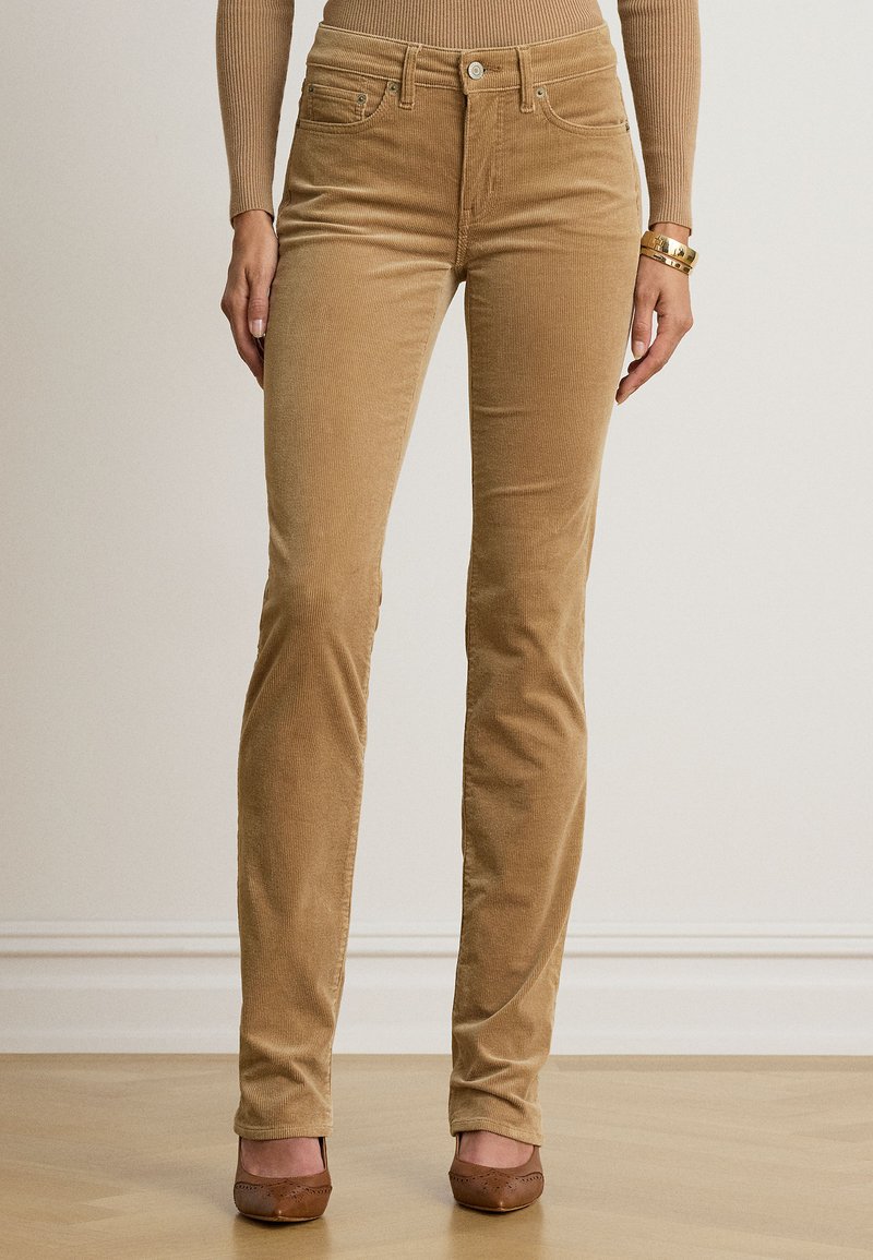 Μπεζ παντελόνι κορδόνι στενής εφαρμογής, φορεμένο με καφέ παπούτσια με χαμηλό τακούνι και ασορτί μπεζ μακρυμάνικη μπλούζα, εμφανιζόμενο από μέση έως πόδια.