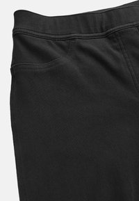 Zwarte denim broek met een gladde textuur, tailleband en een zijzak, met zichtbare stiksels en een slim-fit ontwerp.