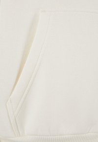 Sudadera color crema con bolsillo frontal, textura suave, dobladillo acanalado y detalles de costura finos.