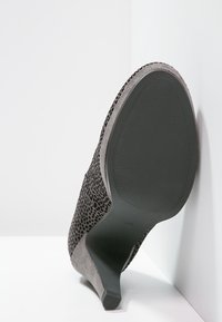 Chaussure à talon haut grise avec un matériau noir texturé, bout arrondi et une semelle en caoutchouc noir lisse présentant une adhérence à motif.